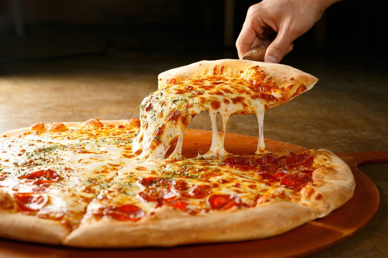 A person is putting cheese on a pizza.